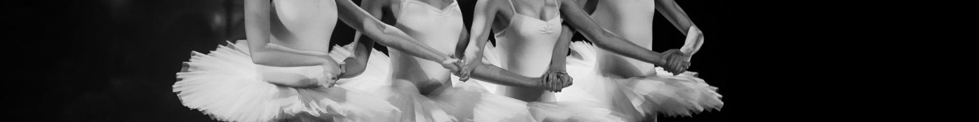 Fyra flickor i balettkjol håller händer.
