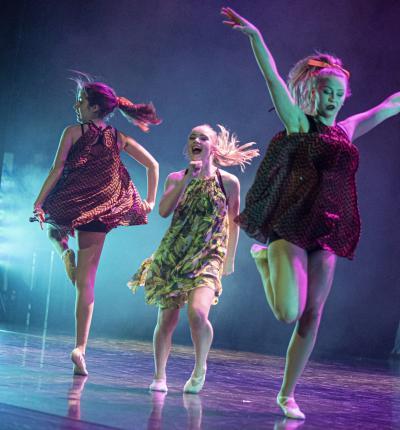 Tre dansande flickor på en scen.
